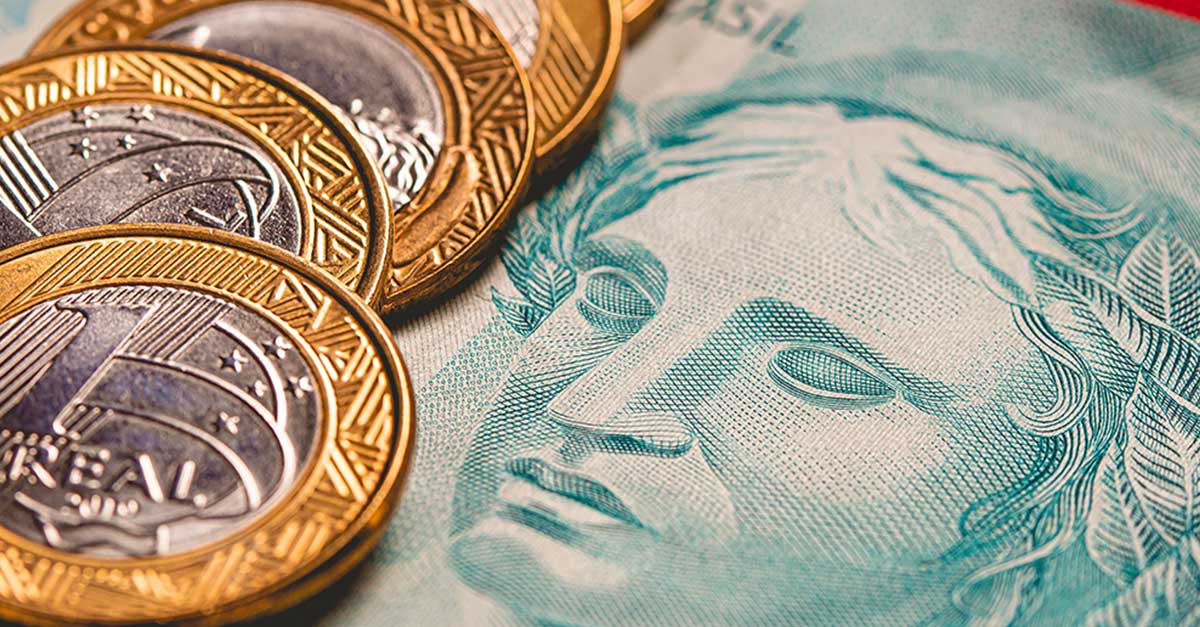 Foto mostra dinheiro em reais: moedas de R$ 1 e cédula de R$ 100